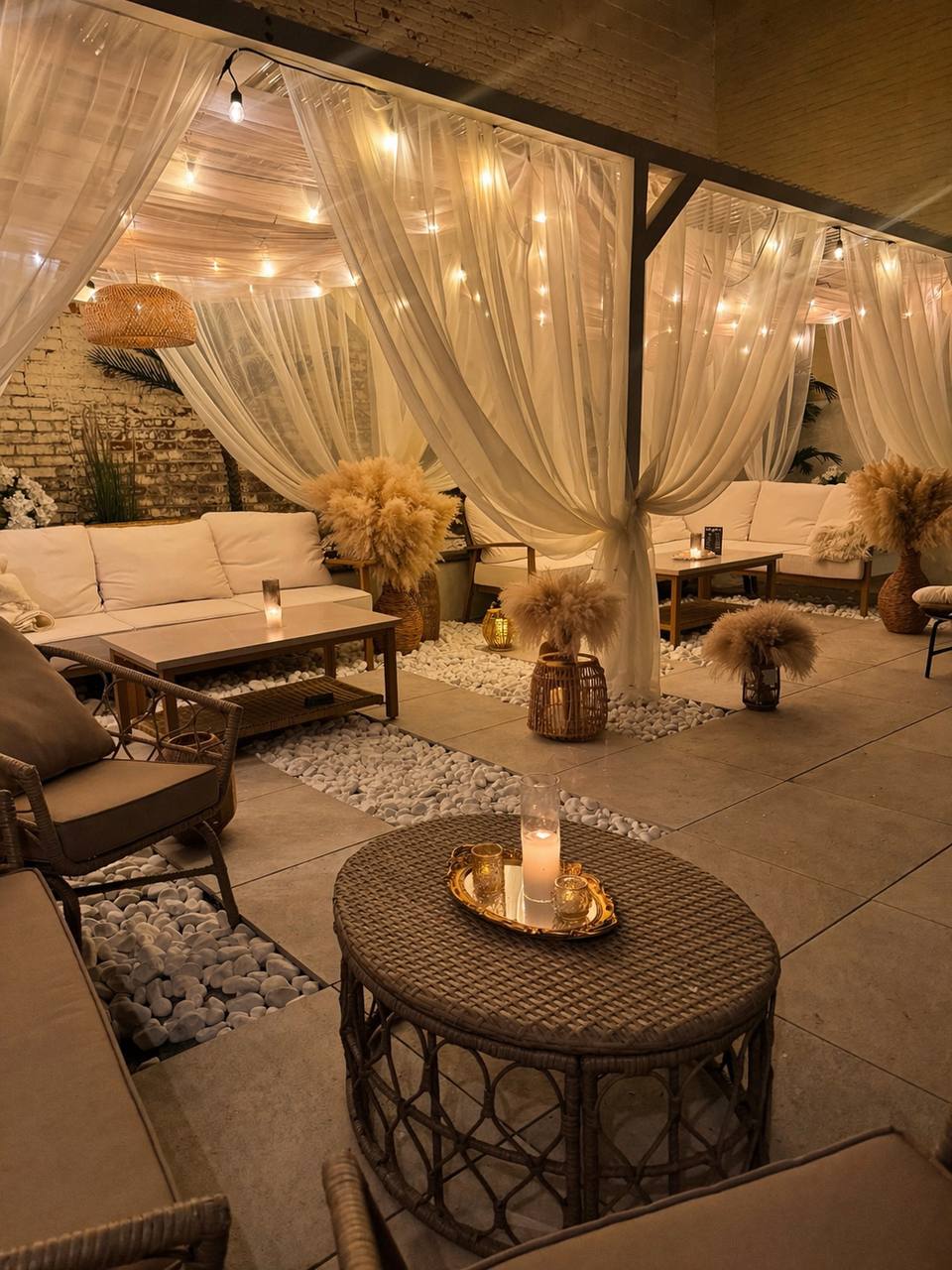 On The Rocks backyard patio with flowing curtains, string lights, and lounge seating