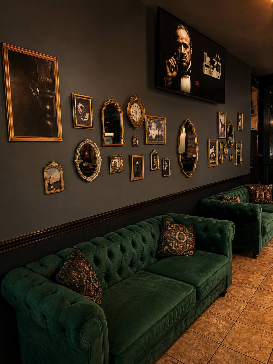 Green velvet lounge seating beneath The Godfather movie wall